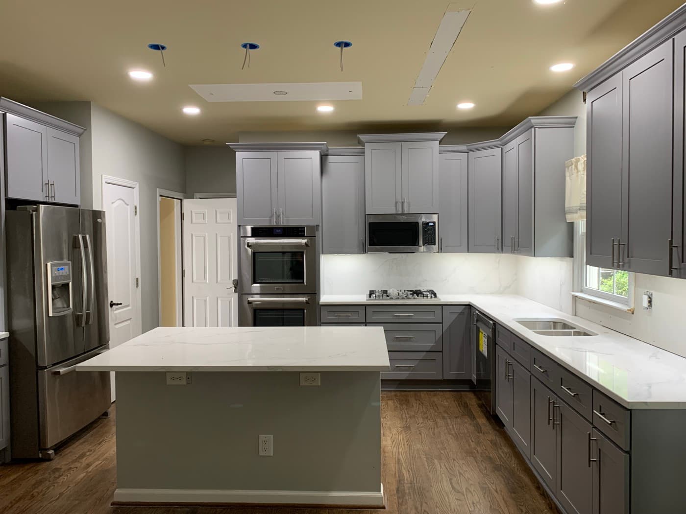 Johns Creek, GA · Custom kitchen cabinets with quartz tops and pendant lighting.