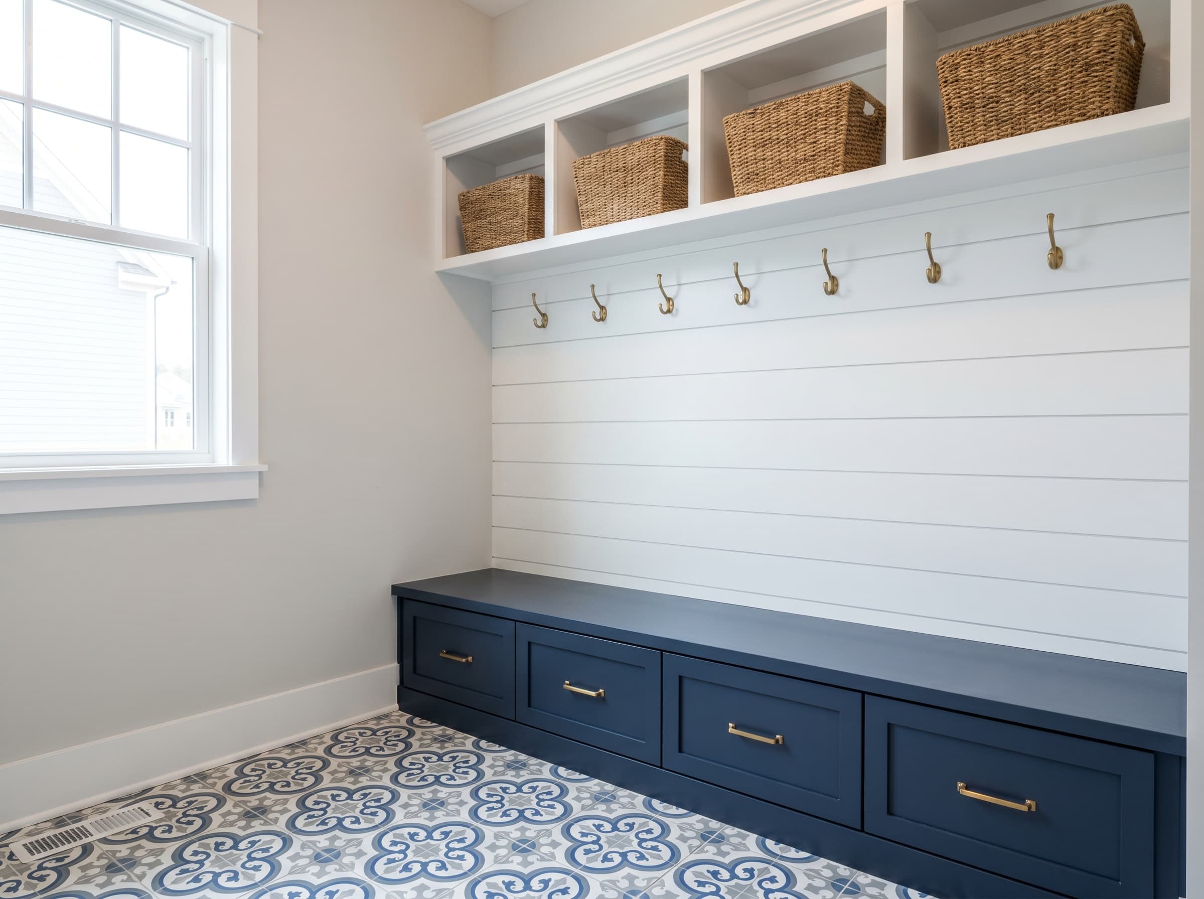 Suwanee, GA · Garage-entry mudroom with navy shaker bench and brass hooks.
